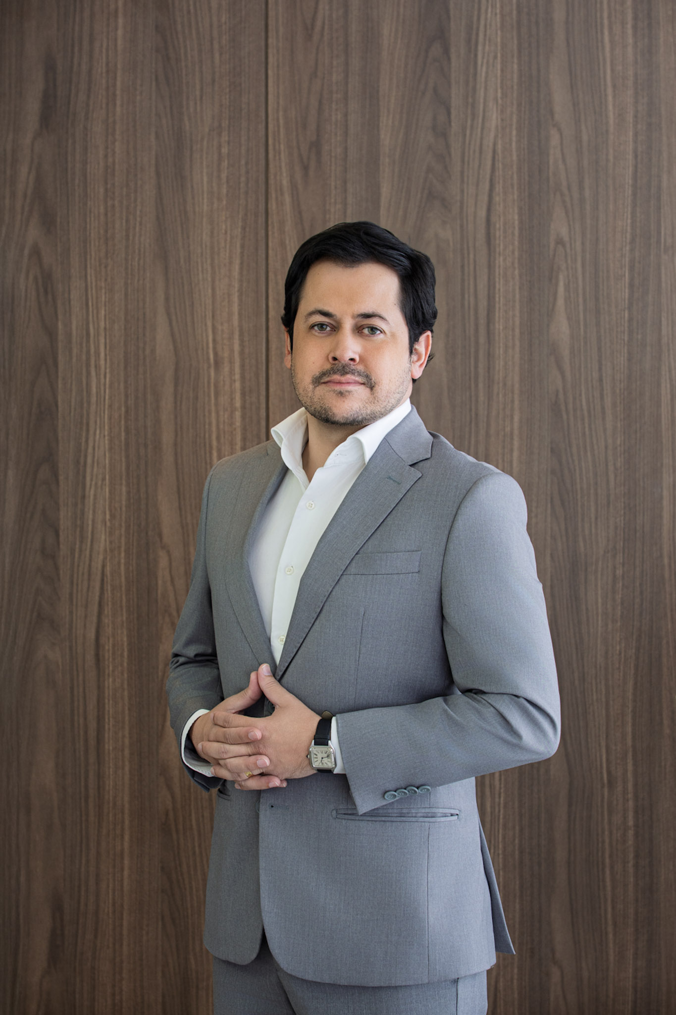 Dr. Diego em pé diante de um painel de madeira